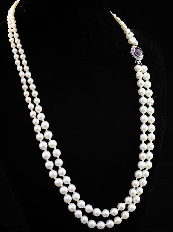 A double strand graduated cultured pearl necklace with a white metal, purple tourmaline and diamond set circular clasp, 16.5in.